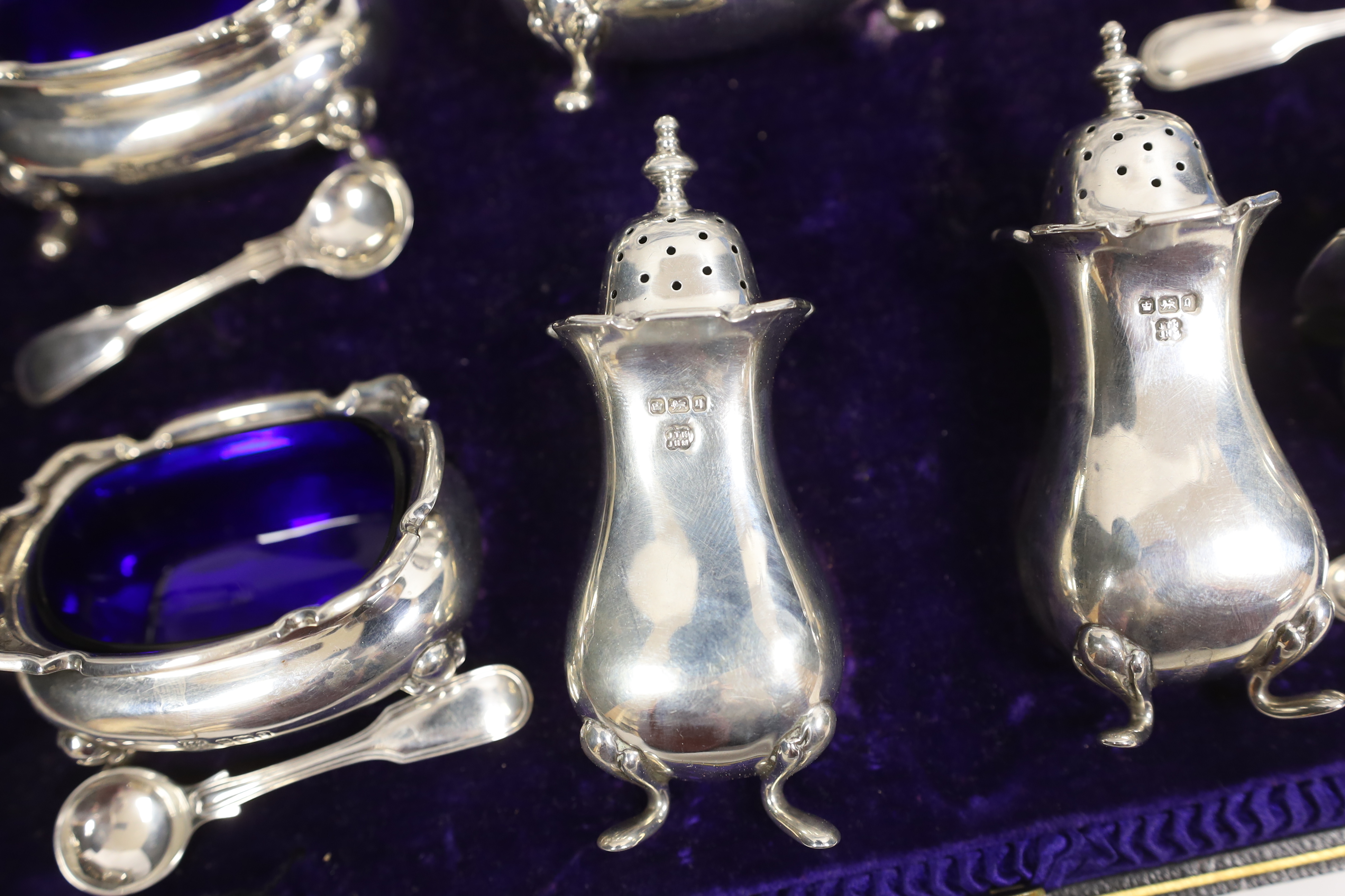 An Edwardian cased silver seven piece condiment set with four matching spoons, Hukin & Heath, Sheffield, 1908, together with an American cased set of parcel gilt sterling grapefruit spoons.